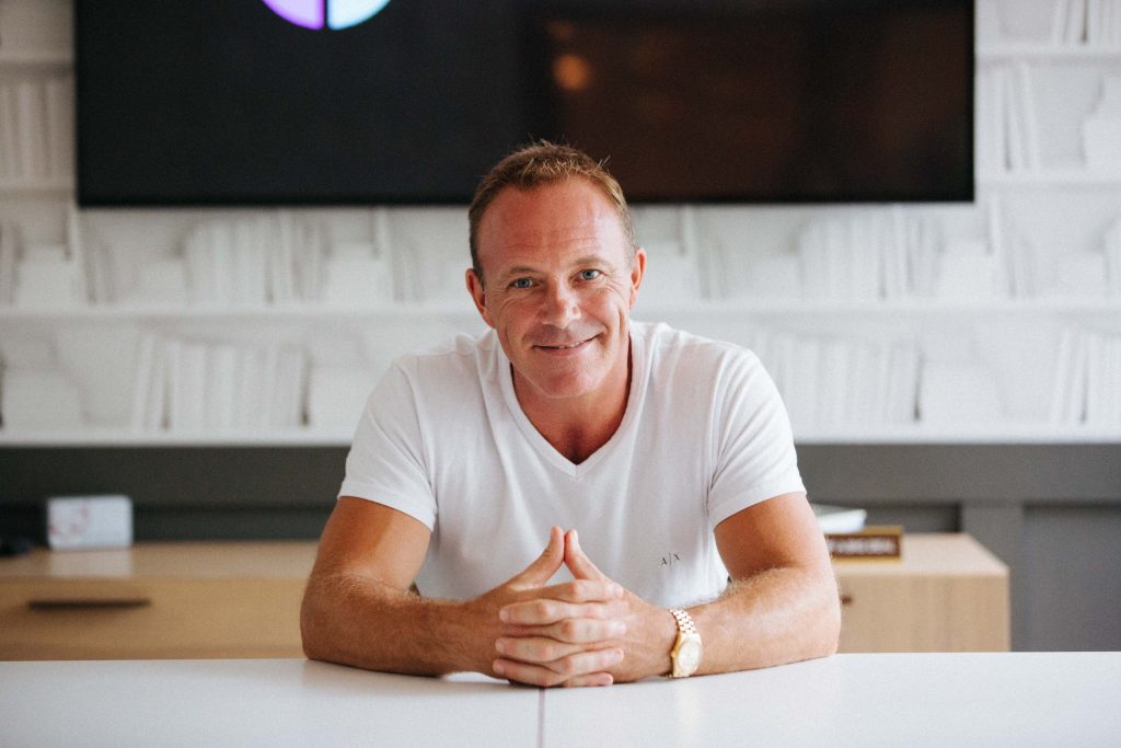 man sits in a white room while wearing a white shirt